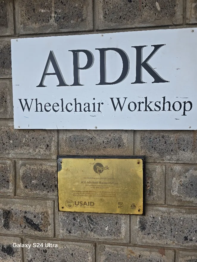 APDK Wheelchair Workshop sign with USAID plaque